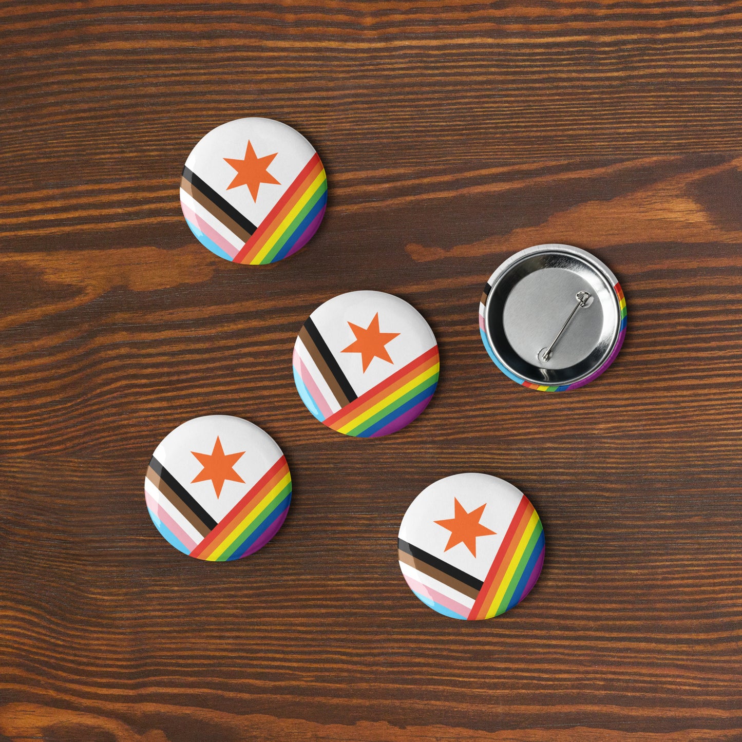 Five Pride version Syracuse, NY city flag button pins lying flat on a wooden surface
