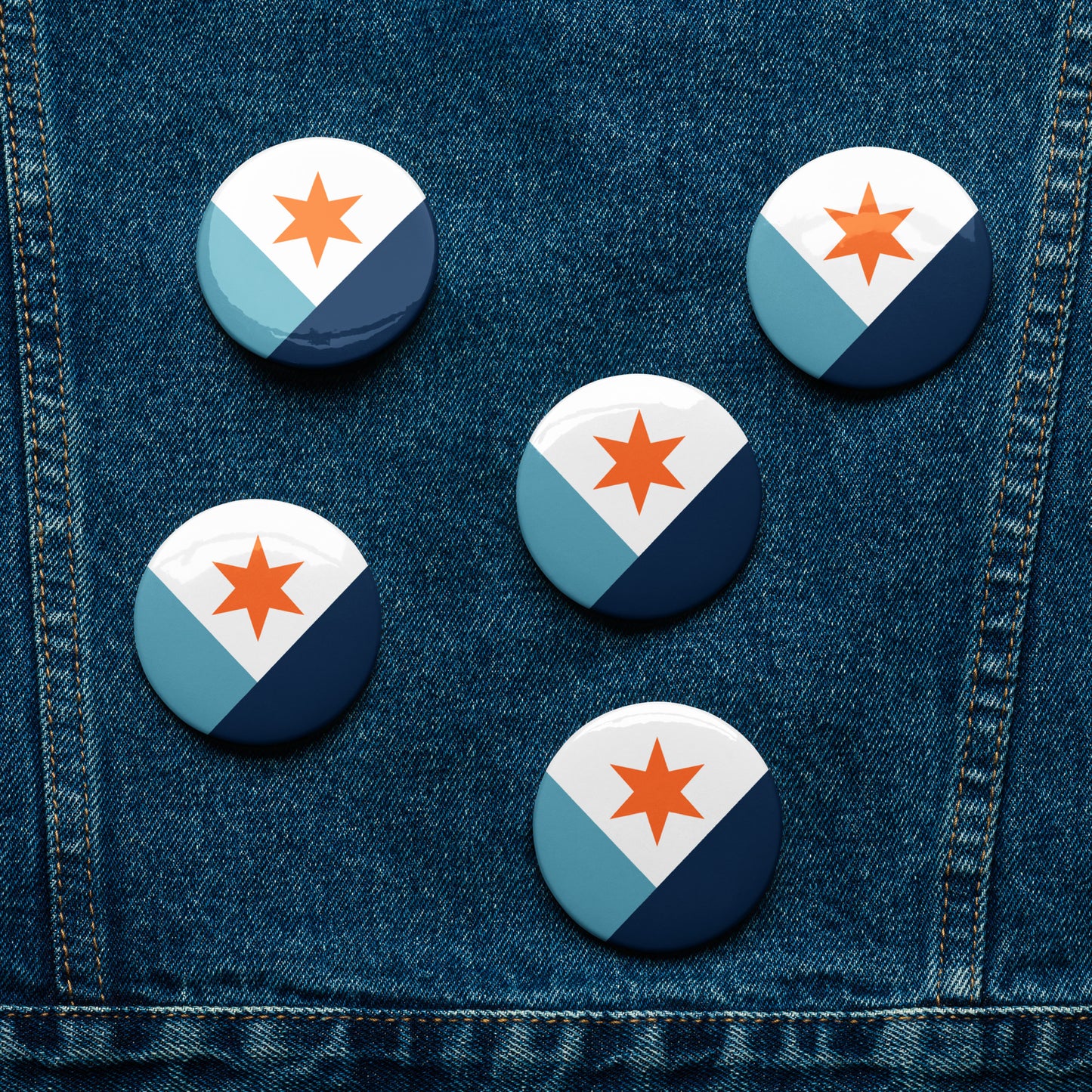 Five Syracuse, NY city flag button pins lying flat on a piece of denim fabric
