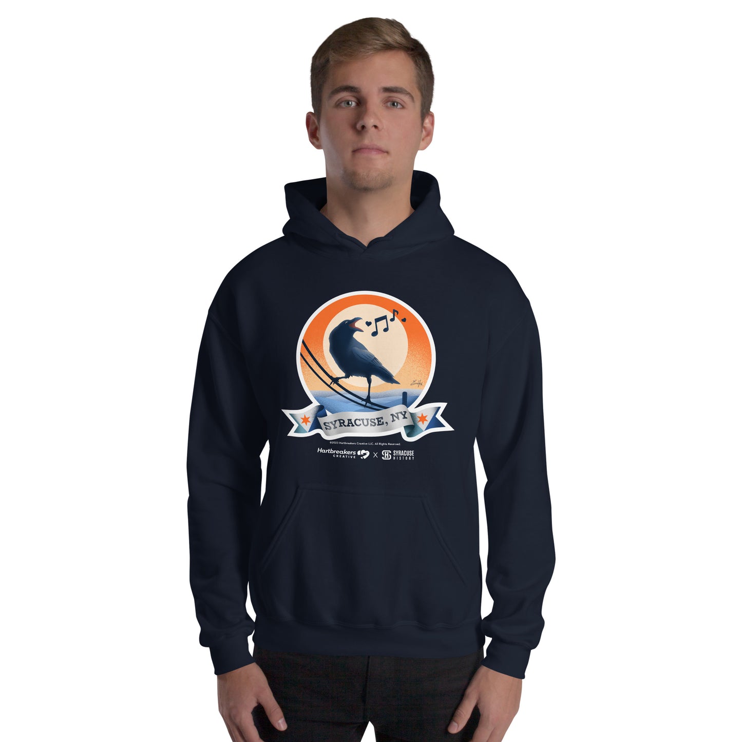 A man wearing a navy hoodie featuring an illustration of a crow on a telephone wire and a banner beneath it that says Syracuse, NY