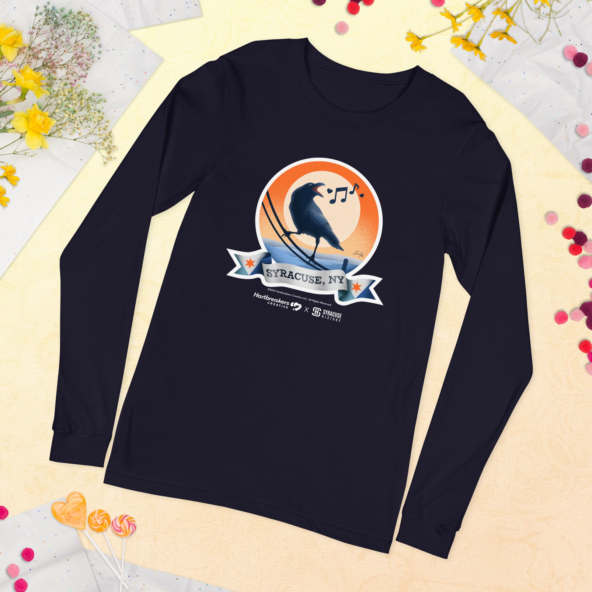 A navy long sleeve T-shirt featuring an illustration of a crow on a telephone wire and a banner beneath it that says Syracuse, NY