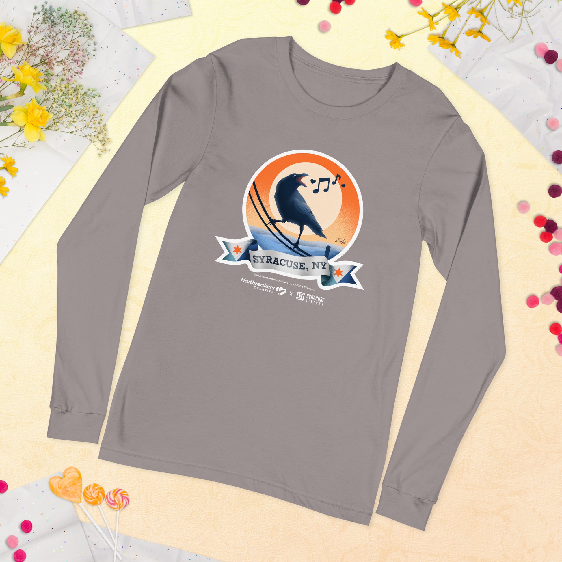 A storm-colored long sleeve T-shirt featuring an illustration of a crow on a telephone wire and a banner beneath it that says Syracuse, NY