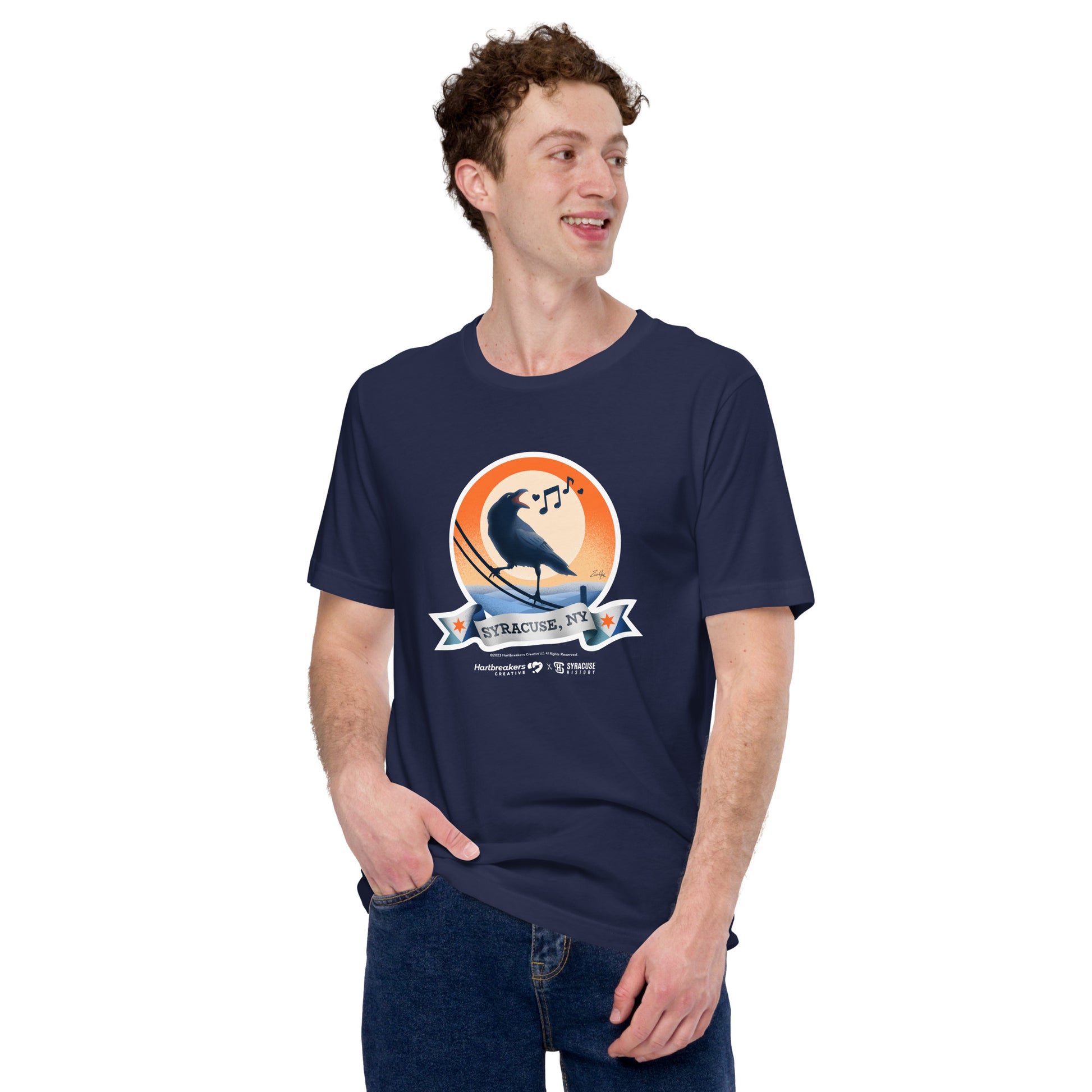 A man wearing a navy T-shirt featuring an illustration of a crow on a telephone wire and a banner beneath it that says Syracuse, NY