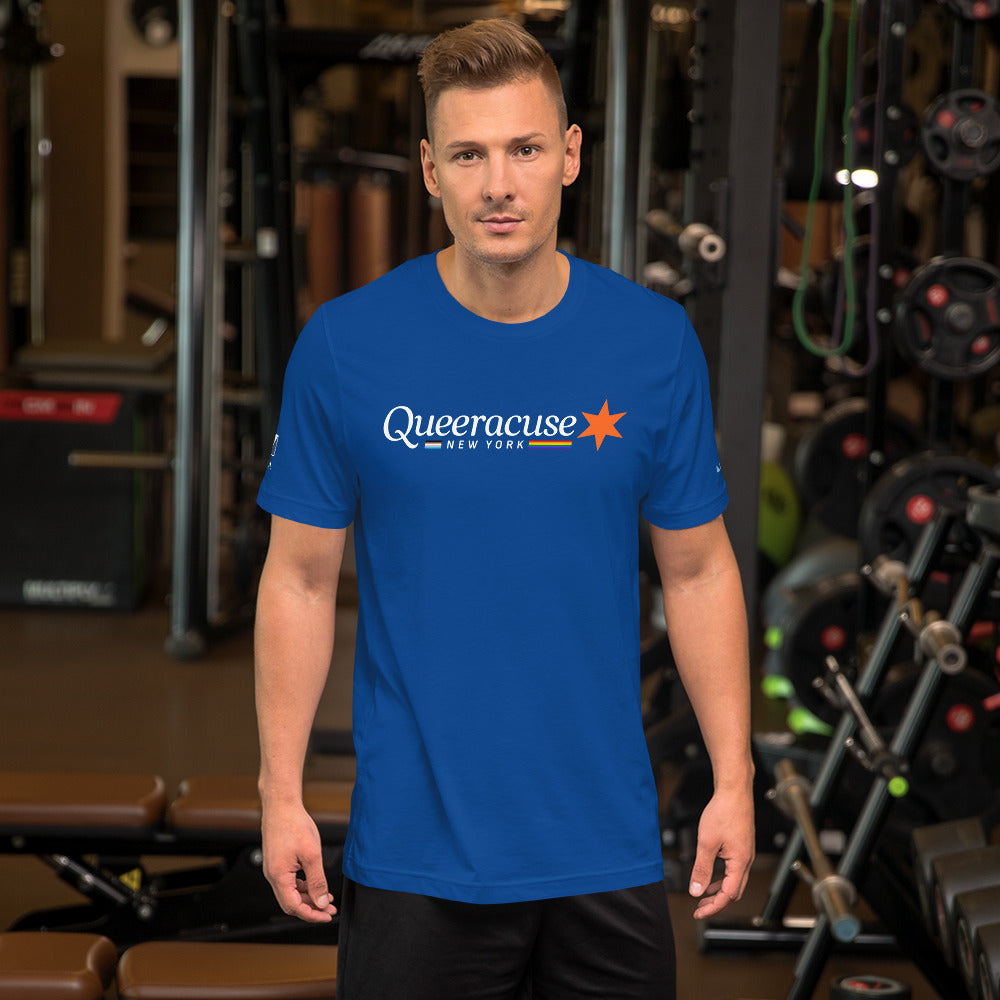 A man in a gym facing us wearing a royal blue Syracuse, NY t-shirt featuring a Queeracuse logo